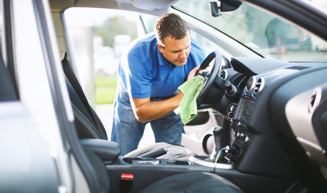 A man maintaining his used car in his home garage.