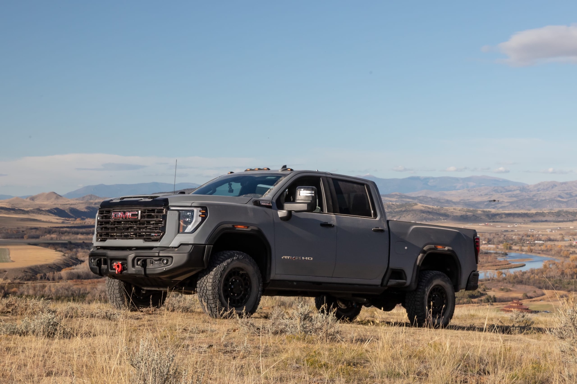 2024 GMC Sierra HD quarter angle driving up a hill of dry plains grass